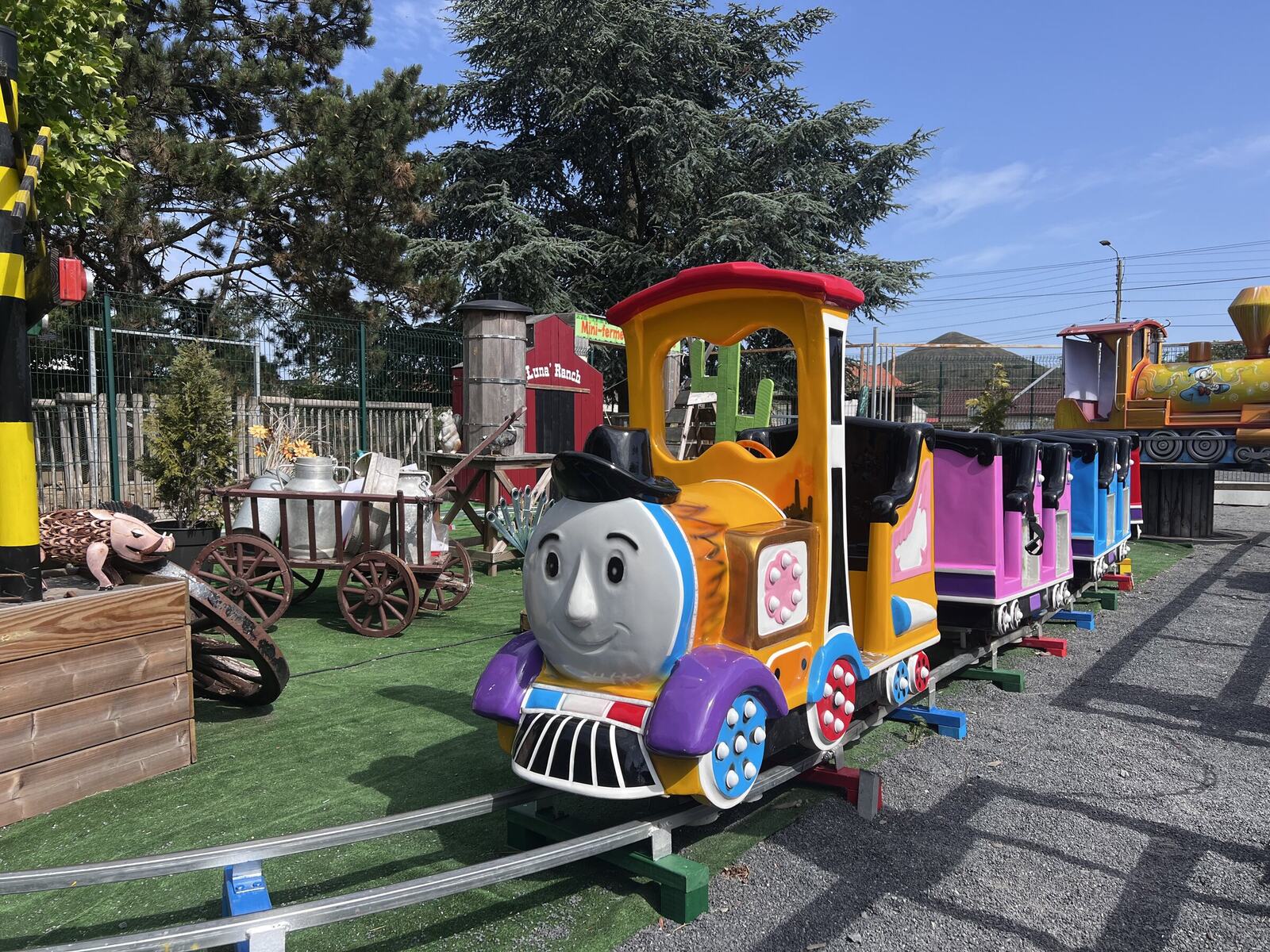 Le Train Western du LunaPark, sa locomotive souriante et ses wagons colorés, sous un ciel bleu